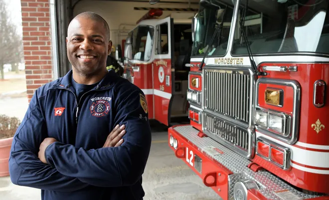 Will Mosley standing with arms crossed in front of fire trucks (Courtesy Photo: Steve Lavana/Telegram & Gazette)