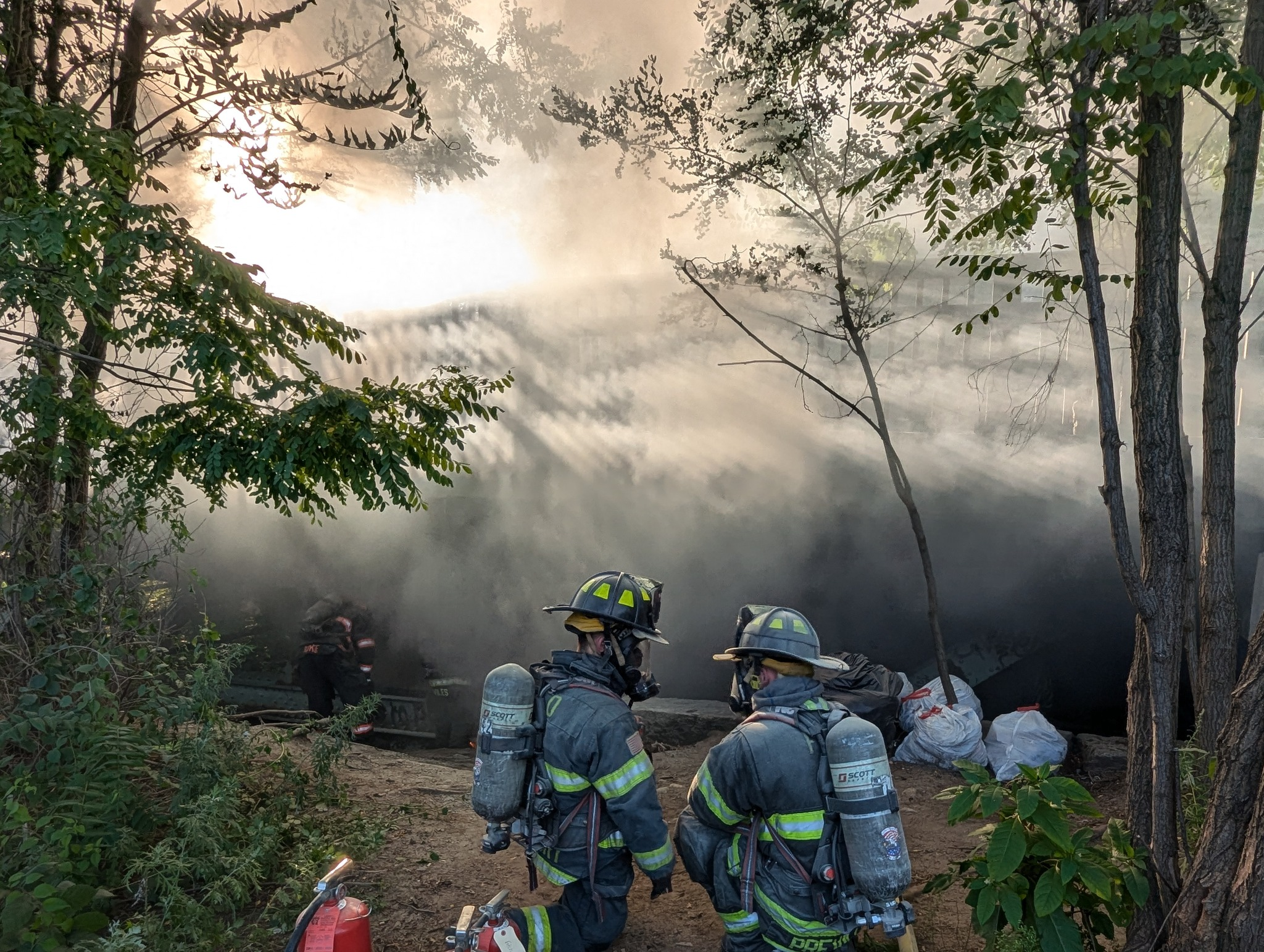Two firefighters standing in front of Rollstone Bridge in Fitchburg which caught fire Saturday, Aug. 24, 2024.