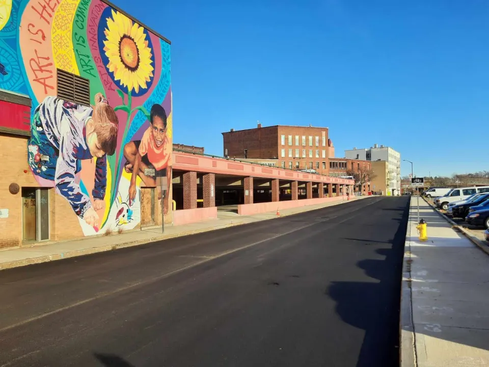 A well-maintained pavement section next to a vibrant mural on Boulder Drive in downtown Fitchburg, demonstrating the city’s maintenance efforts.