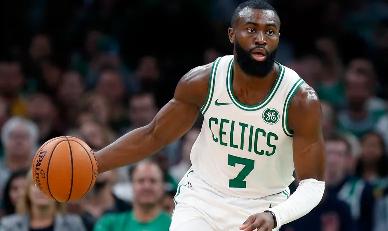 A photo of Celtics star Jaylen Brown in his uniform playing a game with a basketball in his right hand.