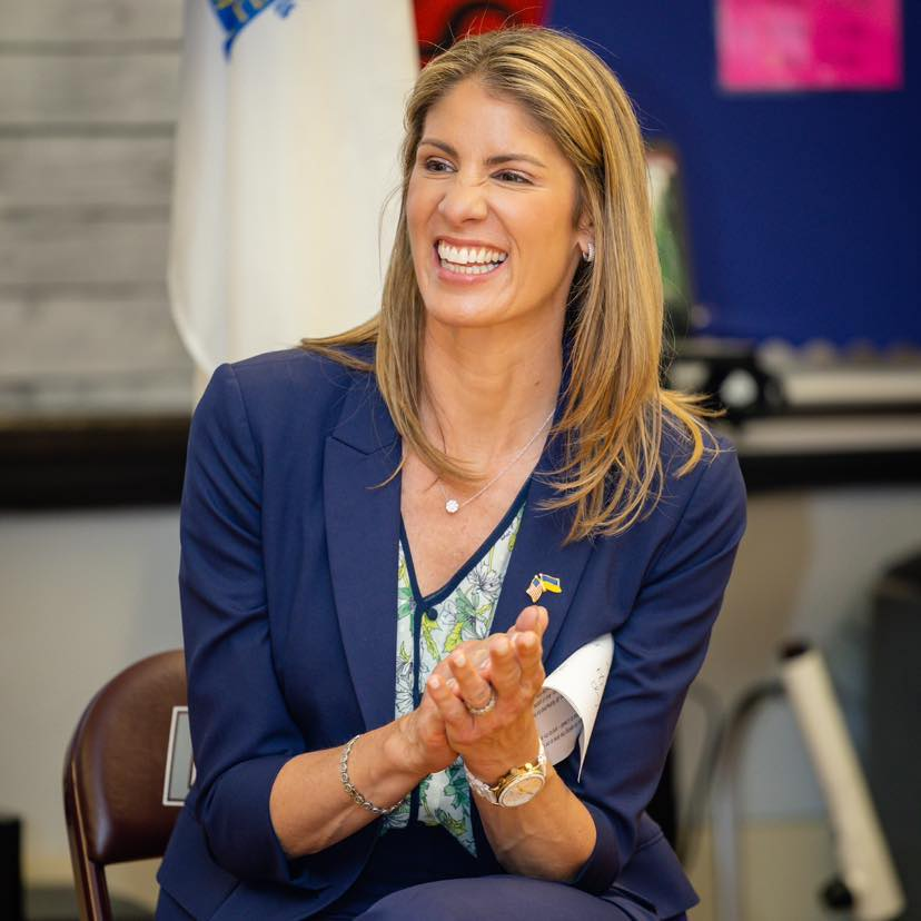 Congresswoman Lori Trahan, smiling and clapping, at a community event in Massachusetts.