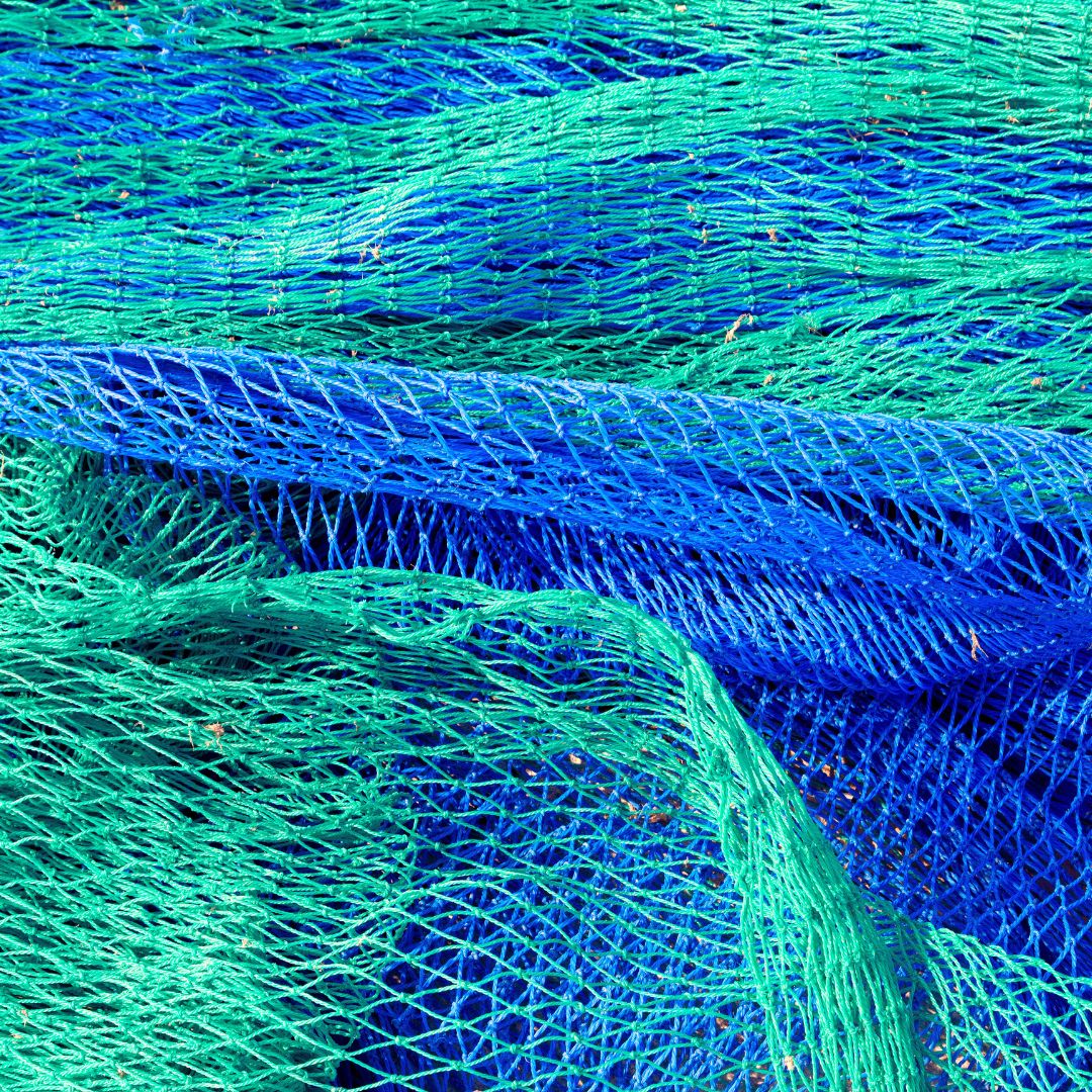 A close-up view of blue and green fishing nets layered together, showing the intricate woven patterns of the netting.