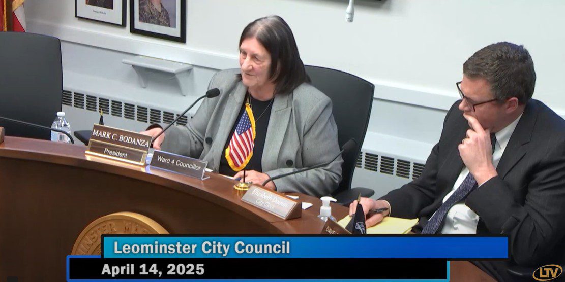 Leominster City Councilor Claire M. Freda, seated at the council bench with a small American flag pinned to her jacket, addresses issues related to Middlesex Integrative Medicine during the April 14, 2025 City Council meeting. Council President Mark C. Bodanza is seated nearby.