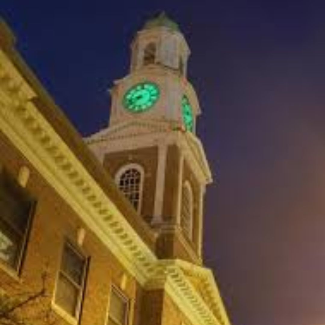 Athol Town Hall's clock tower lit up at night with a green glowing clock face, photographed on October 11, 2024.