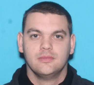 A headshot of Auburn police officer Dominick Boschetto, facing forward against a solid blue background.